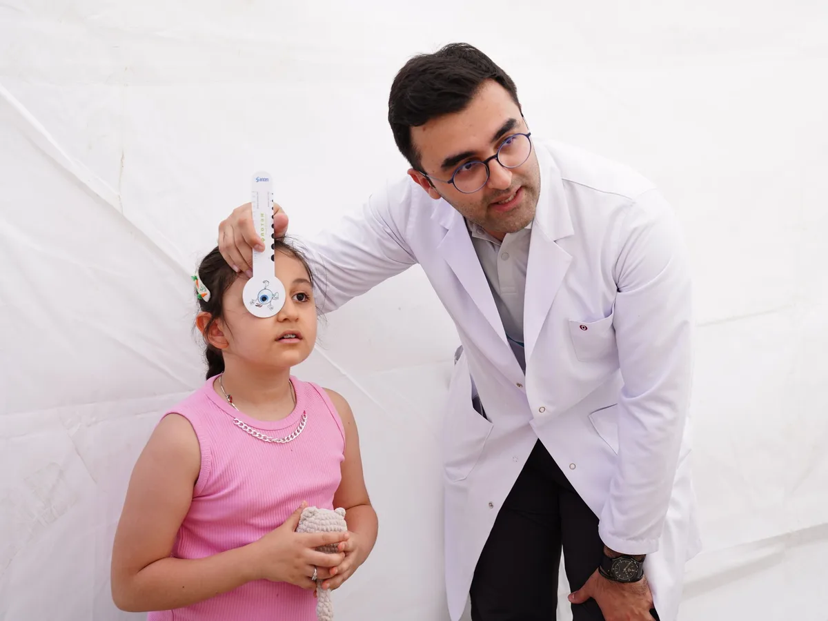Doctor examining a young girl's forehead with a handheld device