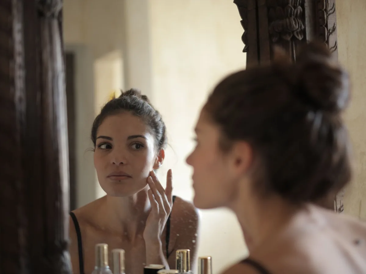 Woman examining her skin in a mirror