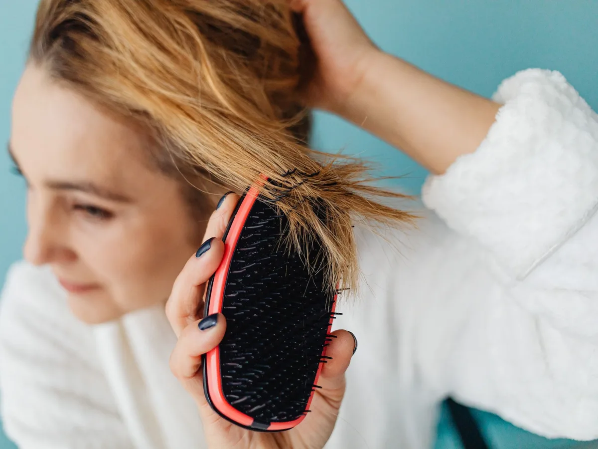 Woman checking her hairbrush for fallen hair