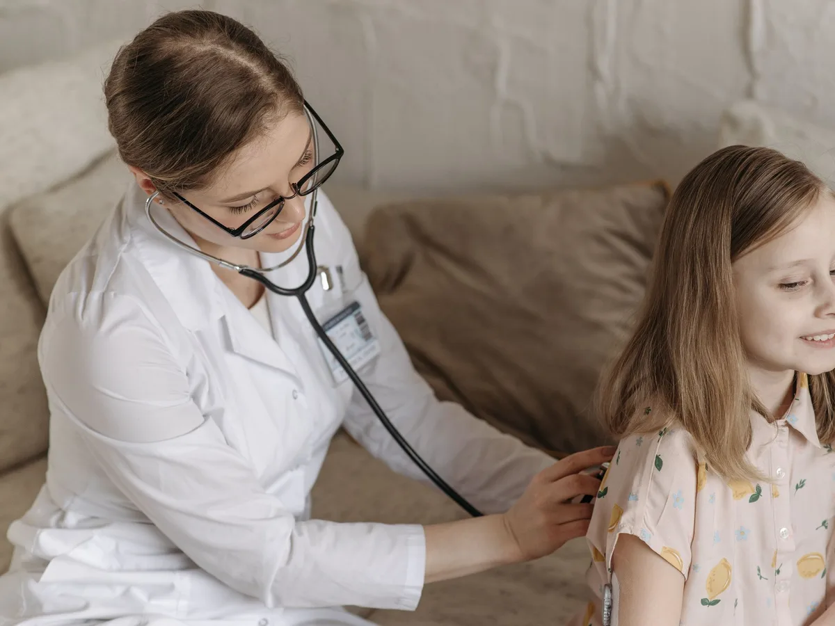 Doctor examining a smiling young girl with a stethoscope